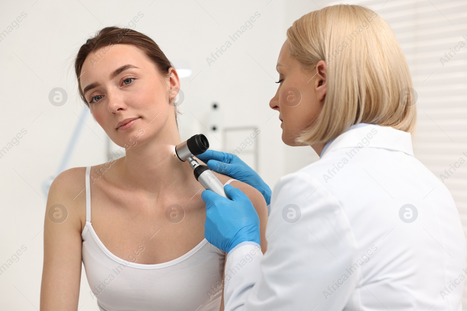 Photo of Dermatologist with dermatoscope examining patient in clinic