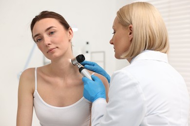 Dermatologist with dermatoscope examining patient in clinic