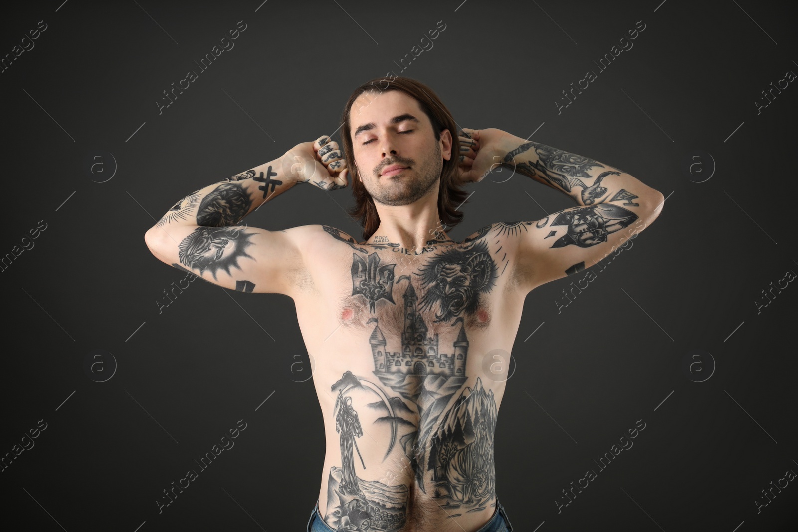 Photo of Young man with tattoos on body against black background