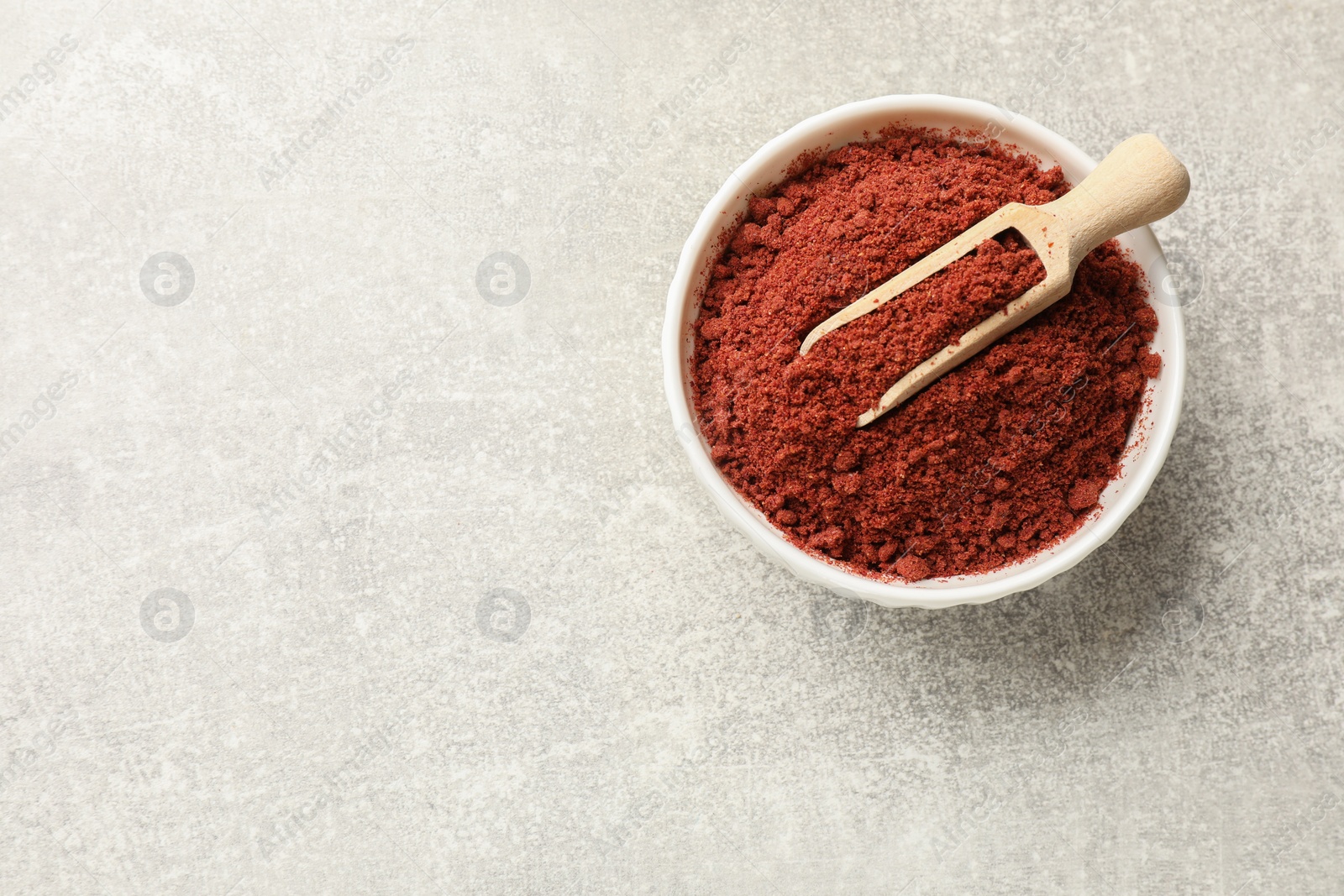 Photo of Cranberry powder in bowl and scoop on light grey table, top view. Space for text