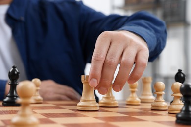 Photo of Man with rook game piece playing chess at checkerboard indoors, closeup