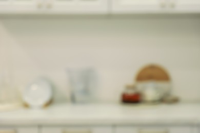 Photo of White stylish kitchen with utensils on countertop, blurred view. Interior design