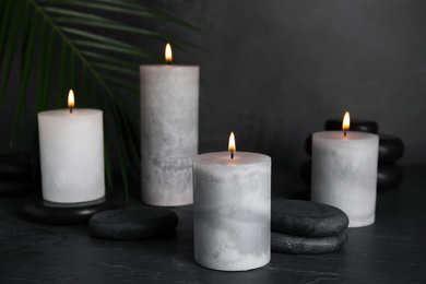 Burning candles and spa stones on black table