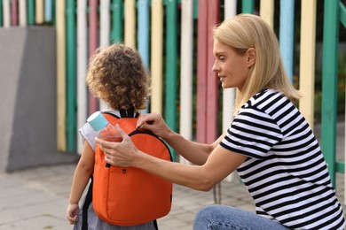 Mother and daughter near kindergarten outdoors, back view