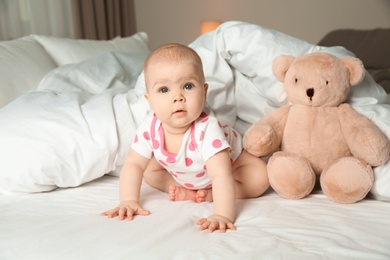 Photo of Cute baby girl with toy on bed at home. Bedtime schedule