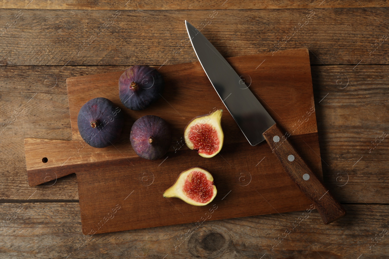 Photo of Whole and cut tasty fresh figs on wooden table, flat lay