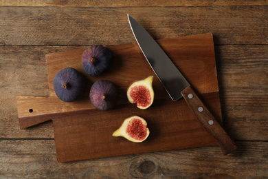 Whole and cut tasty fresh figs on wooden table, flat lay