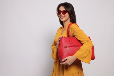 Young woman with stylish bag on white background, space for text