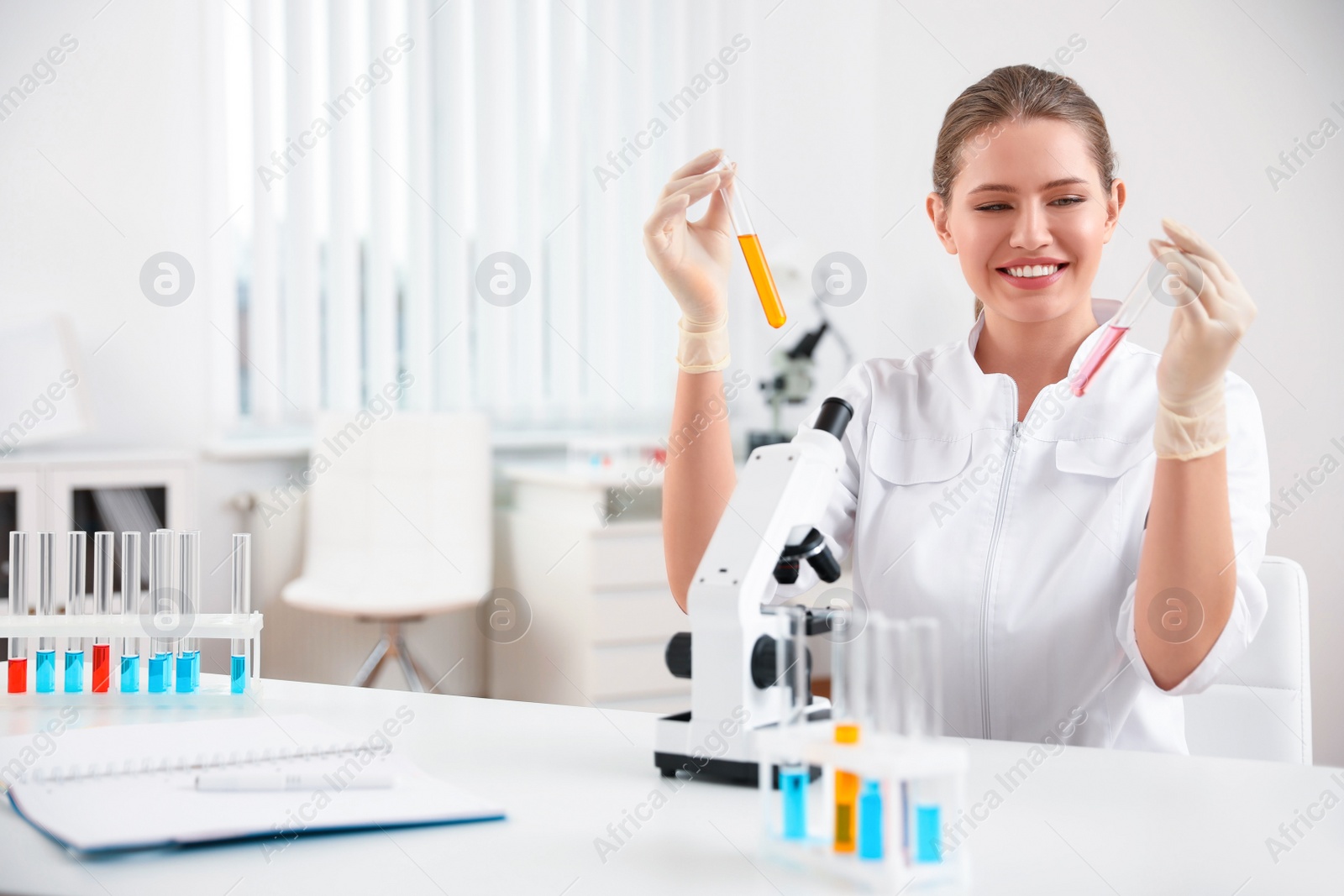 Photo of Scientist with test tubes and microscope at table. Medical research