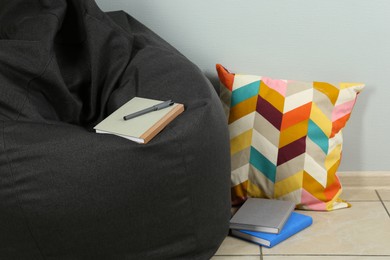 Photo of Black cozy bean bag chair near light grey wall in room