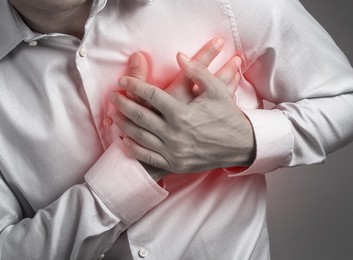 Man having heart attack on grey background, closeup