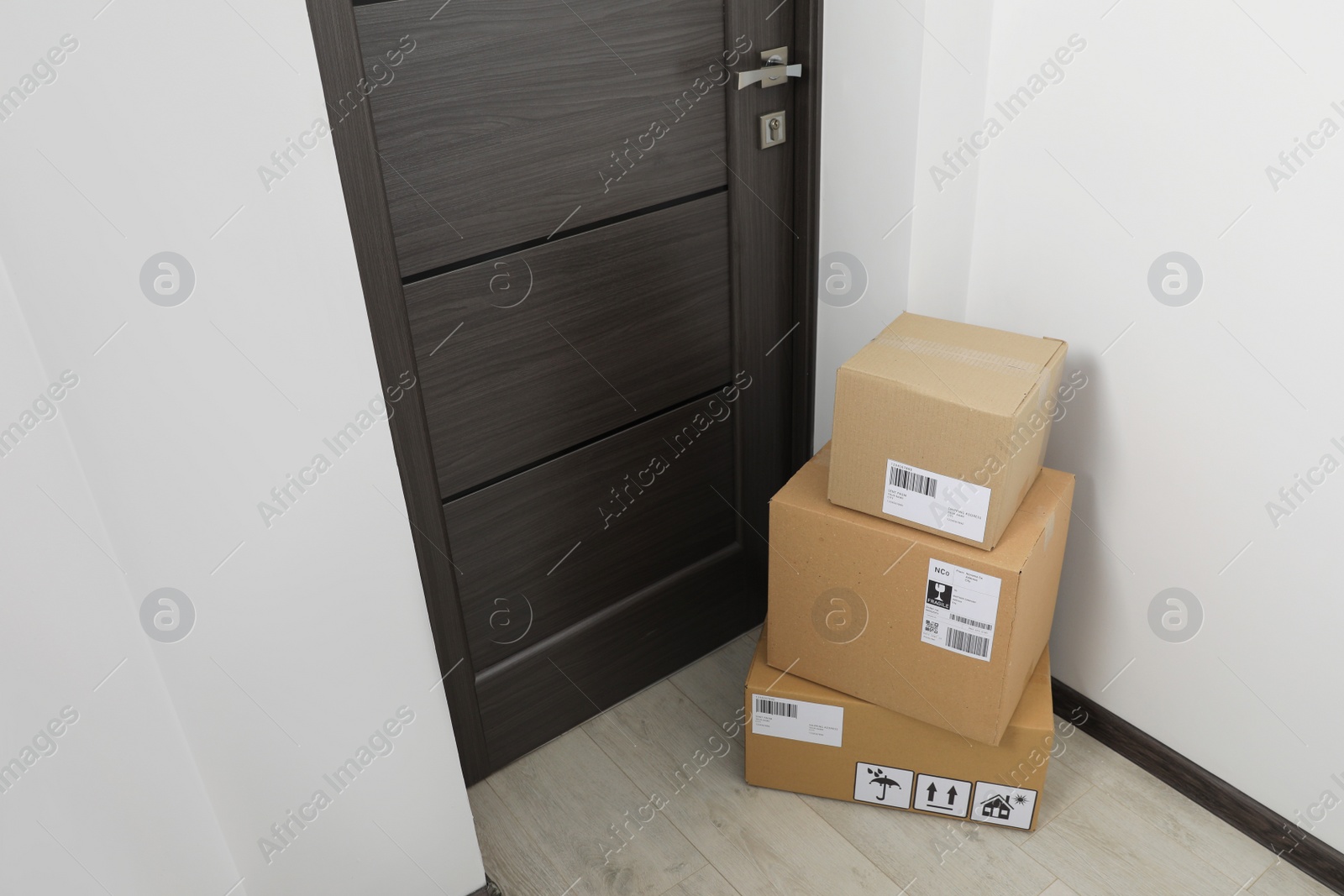 Photo of Cardboard boxes on floor near entrance. Parcel delivery service