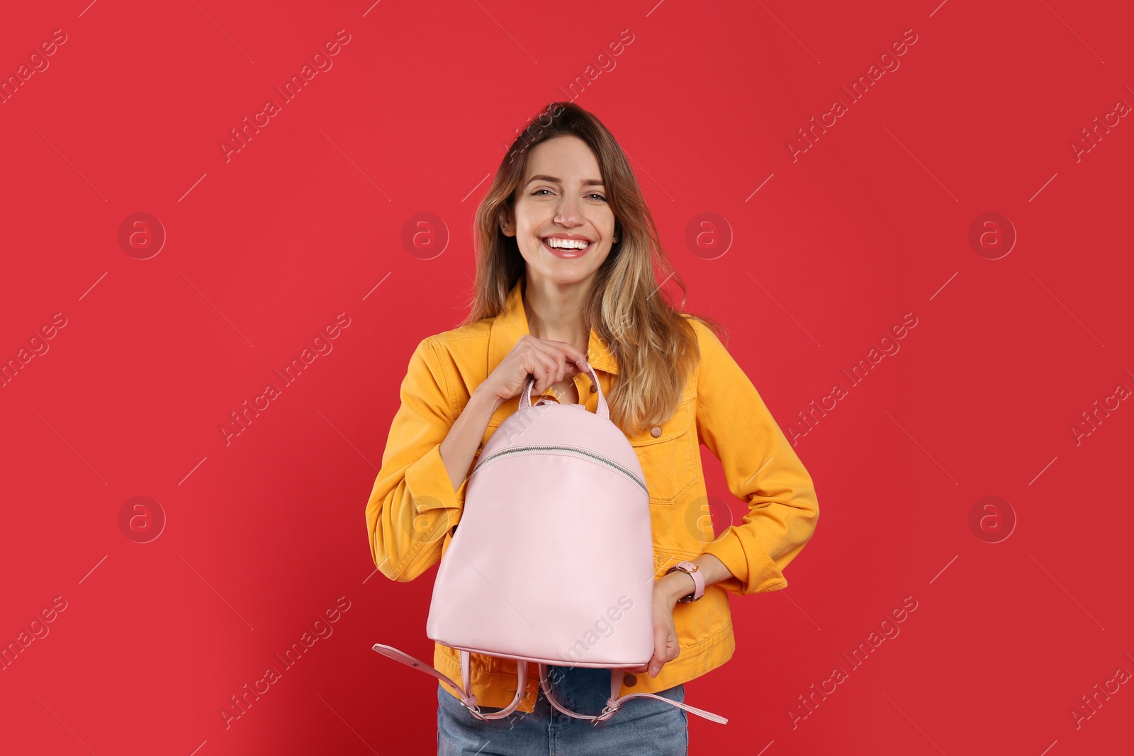 Photo of Happy woman with backpack on red background