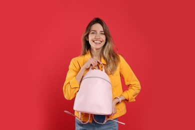 Photo of Happy woman with backpack on red background