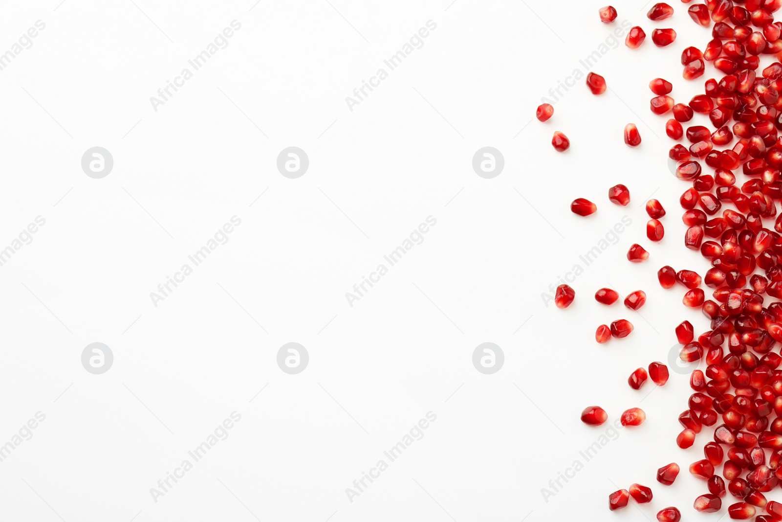 Photo of Many ripe juicy pomegranate grains on white background, flat lay. Space for text