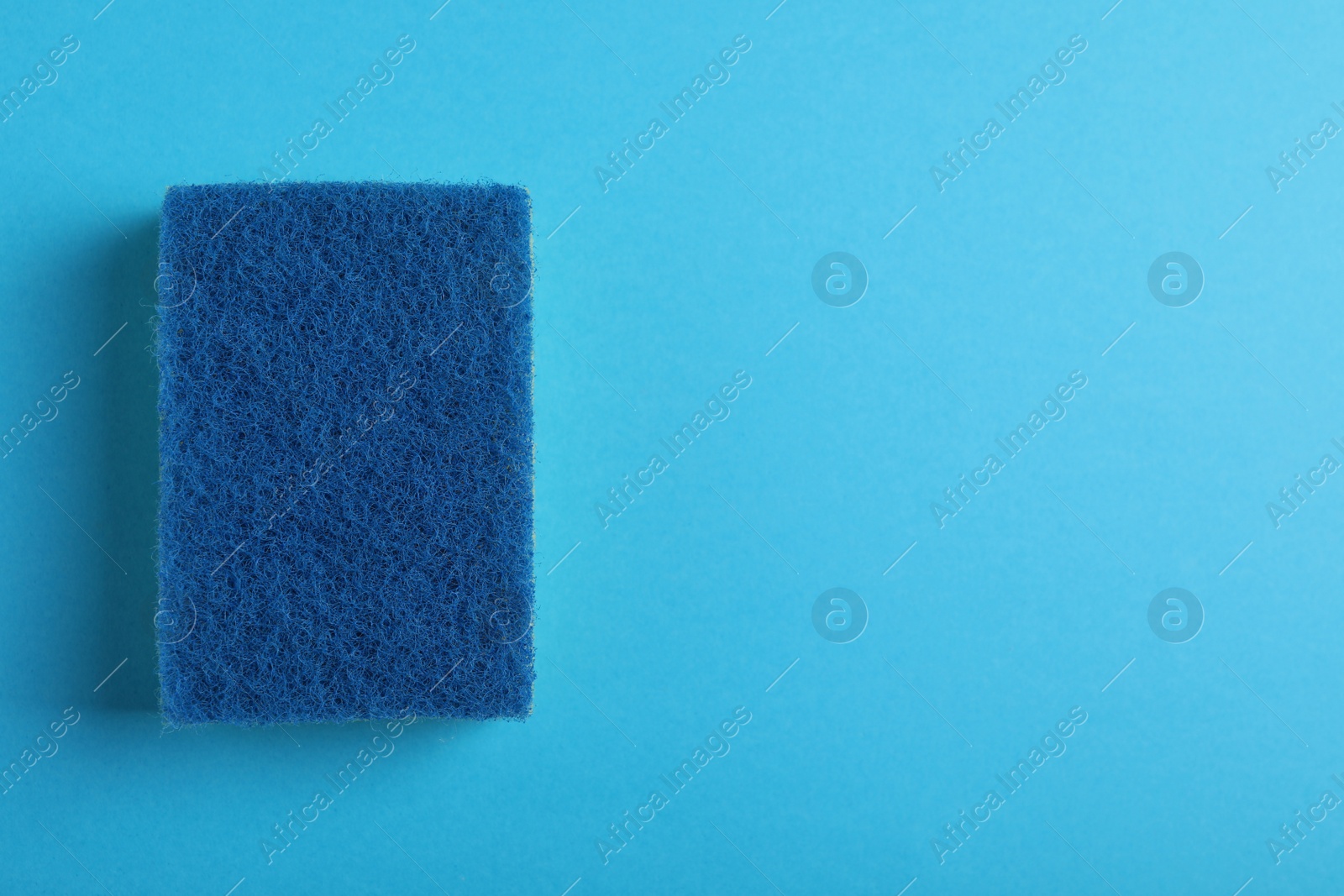 Photo of New sponge on light blue background, top view. Space for text