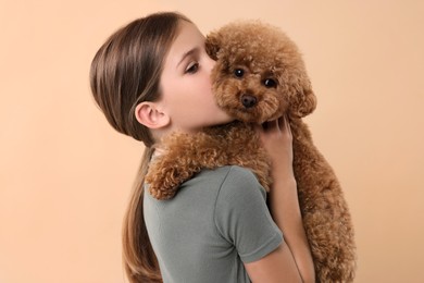 Photo of Little child with cute puppy on beige background. Lovely pet