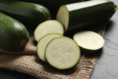 Whole and cut ripe zucchinis on black table, closeup