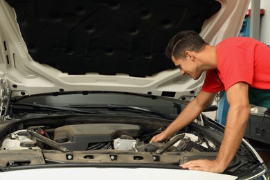 Professional mechanic checking modern car at automobile repair shop