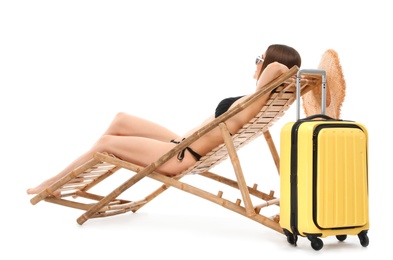 Young woman with suitcase on sun lounger against white background. Beach accessories