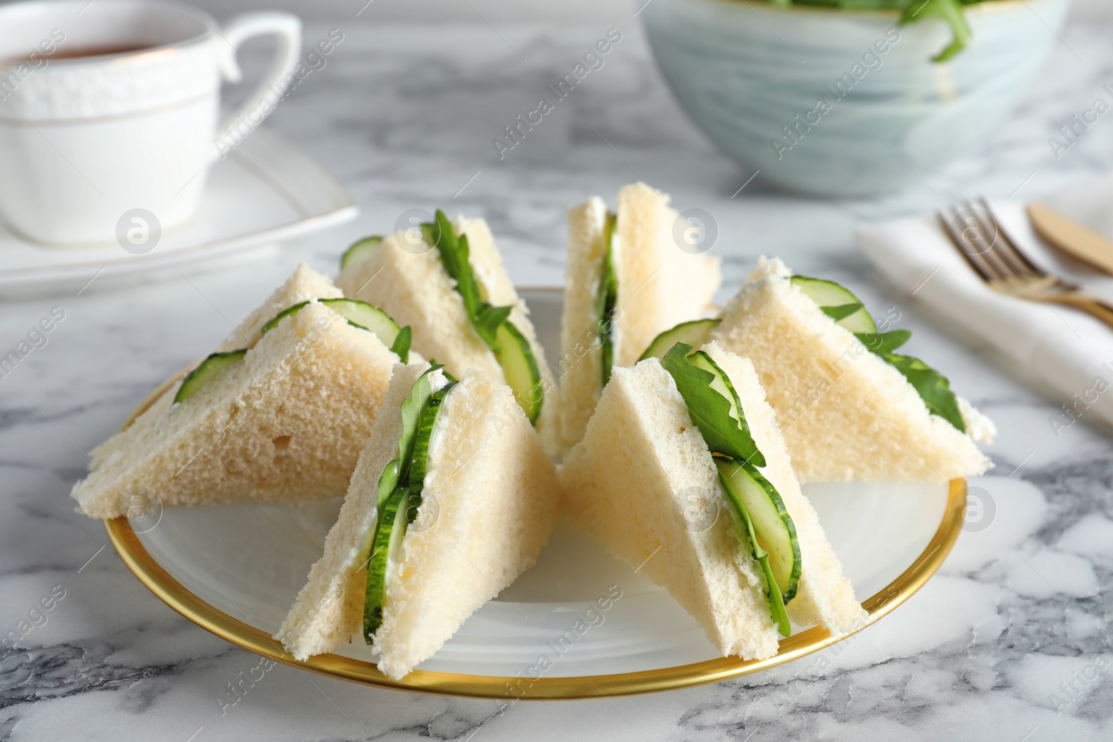 Photo of Plate with traditional English cucumber sandwiches on table