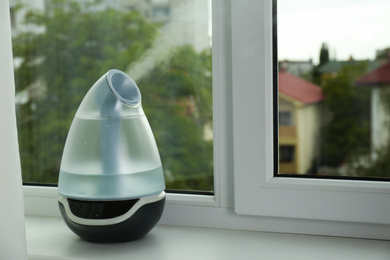 Photo of Modern air humidifier on windowsill indoors. Space for text