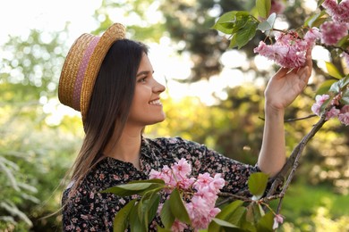 Photo of Beautiful young woman near blossoming sakura tree in park