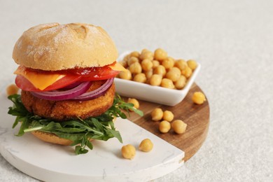 Tasty vegetarian burger with chickpea cutlet on white table, space for text