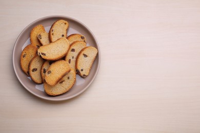 Plate of sweet hard chuck crackers with raisins on wooden table, top view. Space for text