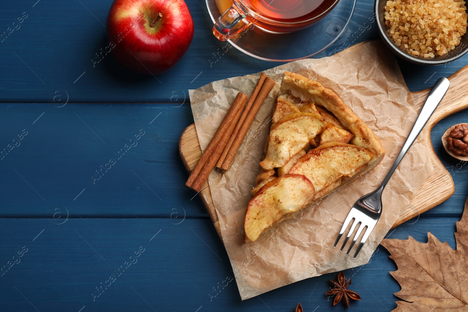 Photo of Flat lay composition with delicious apple pie, ingredients and tea on blue wooden table. Space for text