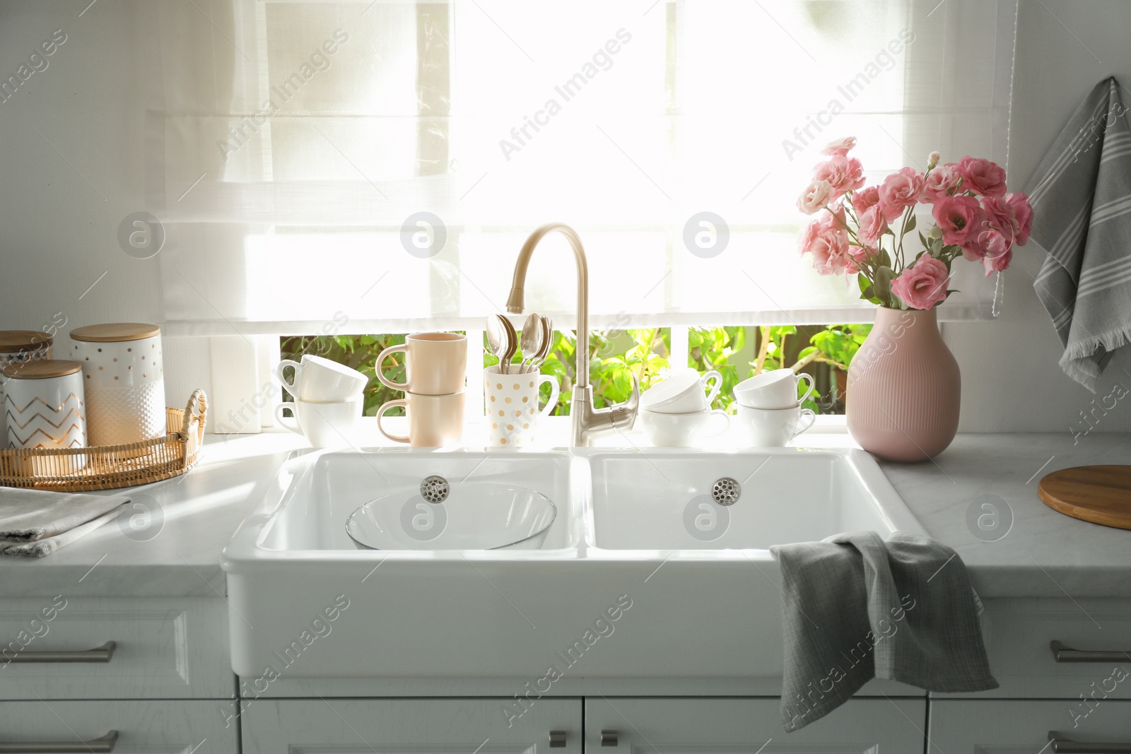 Photo of Vase with flowers on countertop near sink against window in kitchen