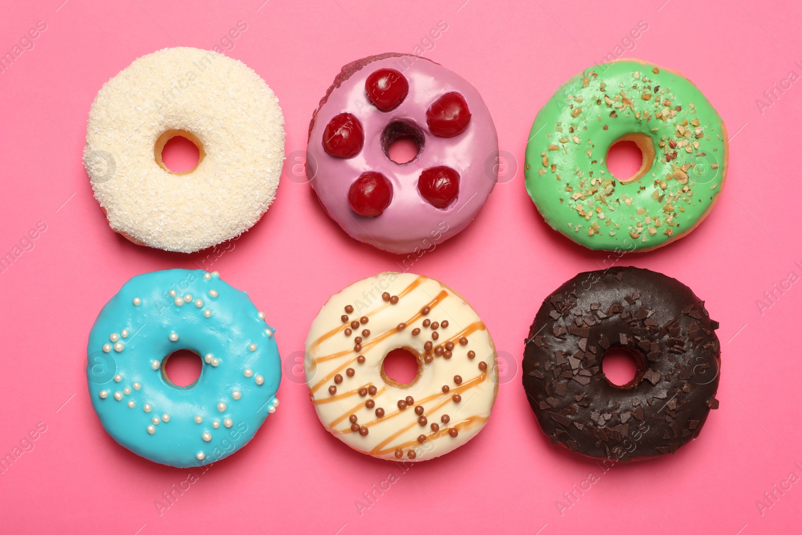 Photo of Different delicious glazed doughnuts on pink background, flat lay