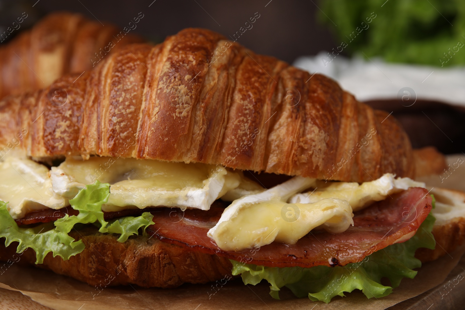 Photo of Tasty croissant with brie cheese and bacon, closeup