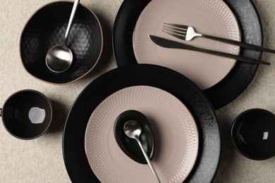 Photo of Stylish table setting. Dishes, cutlery and cups on light surface, flat lay