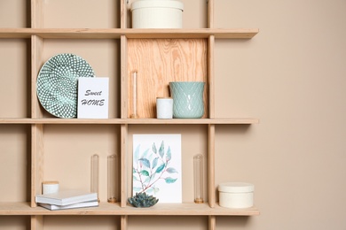 Photo of Wooden shelves with different decorative elements on beige wall