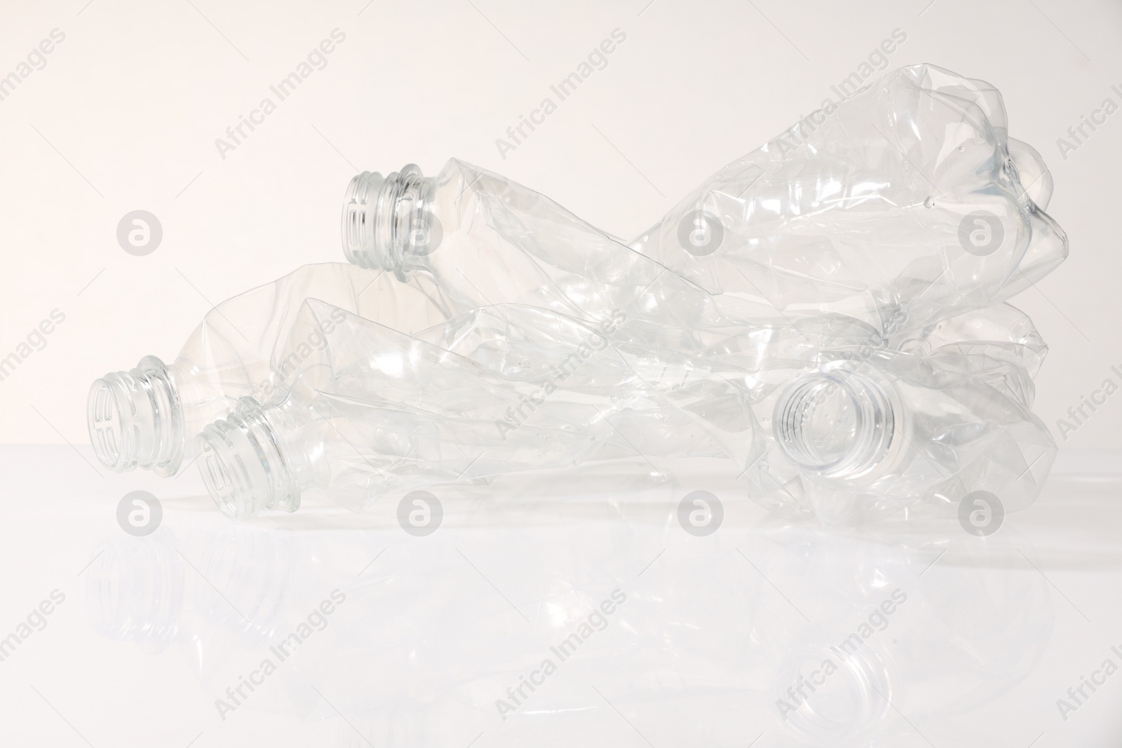 Photo of Crumpled disposable plastic bottles on white background