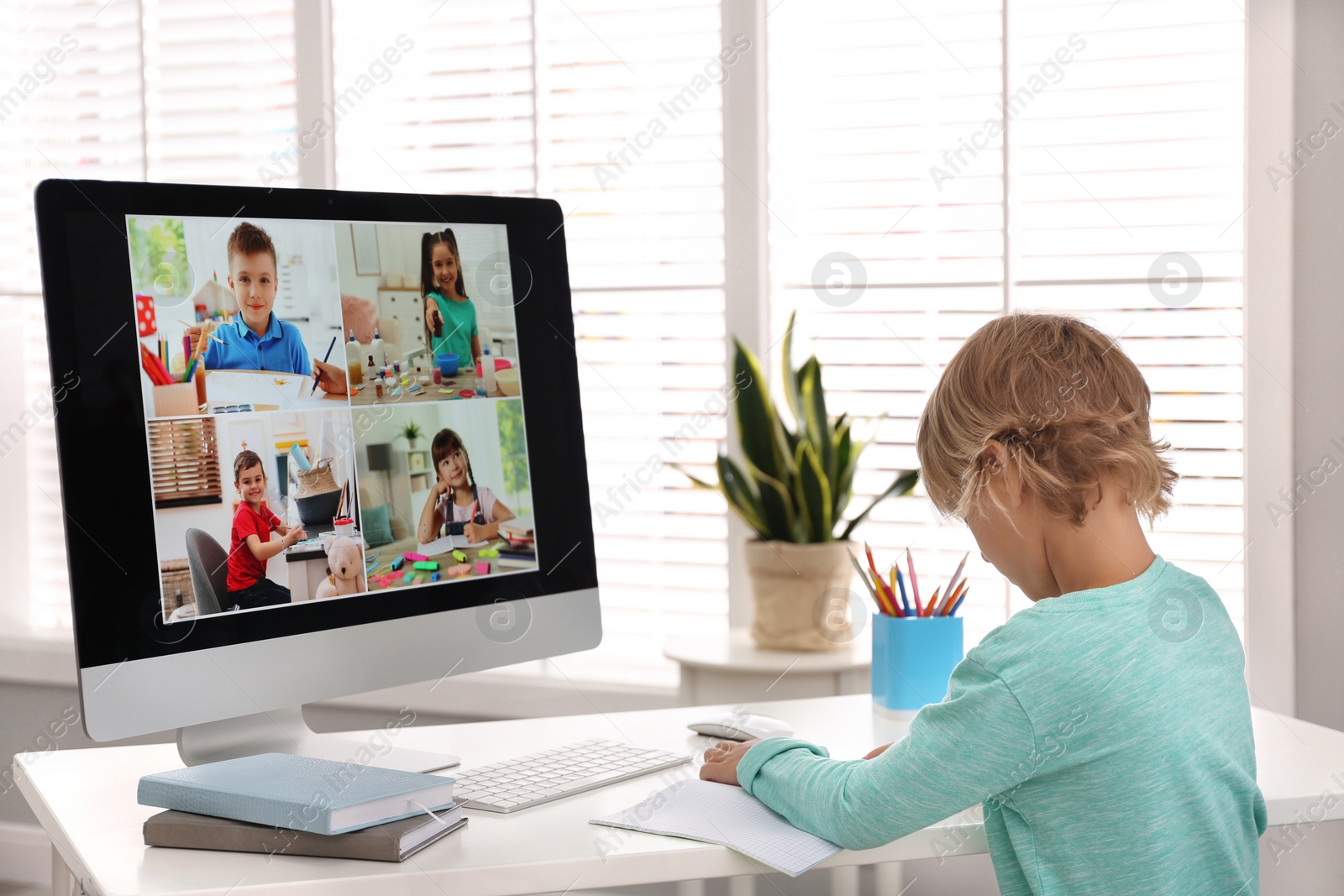 Photo of Little boy studying with classmates via video conference at home. Distance learning during COVID-19 pandemic