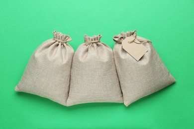 Photo of Tied burlap bags on green background, flat lay