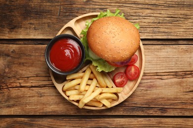 Photo of French fries, tasty burger and sauce on wooden table, top view