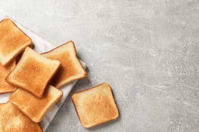 Photo of Slices of tasty toasted bread on light grey table, flat lay. Space for text