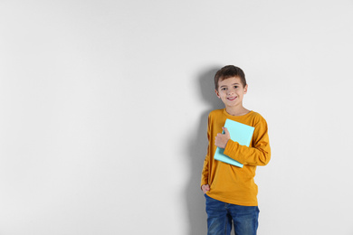 Photo of Cute little boy with book on light background, space for text