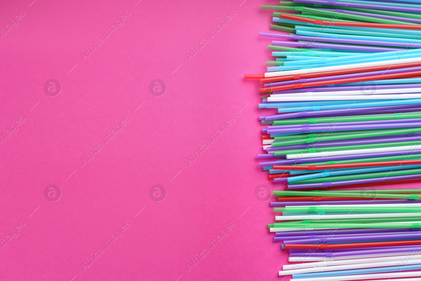 Photo of Colorful plastic drinking straws on pink background, flat lay. Space for text