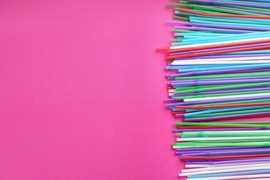 Colorful plastic drinking straws on pink background, flat lay. Space for text