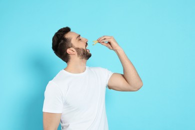 Man eating French fries on light blue background