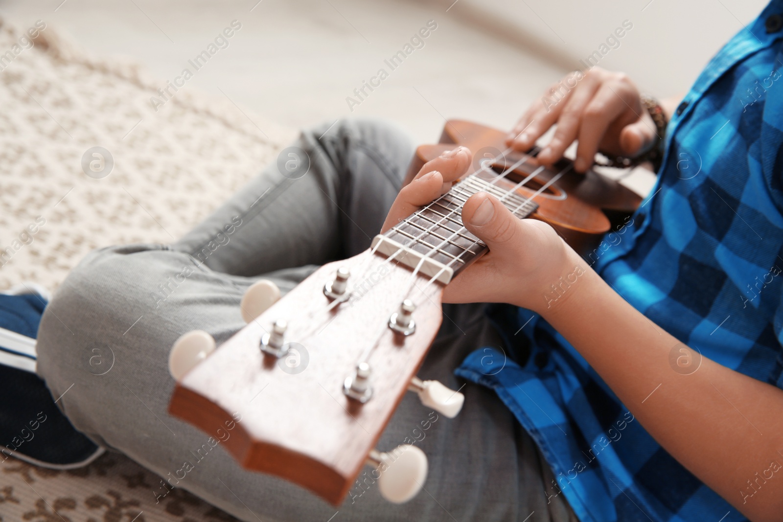 Photo of Little boy playing guitar on floor, closeup