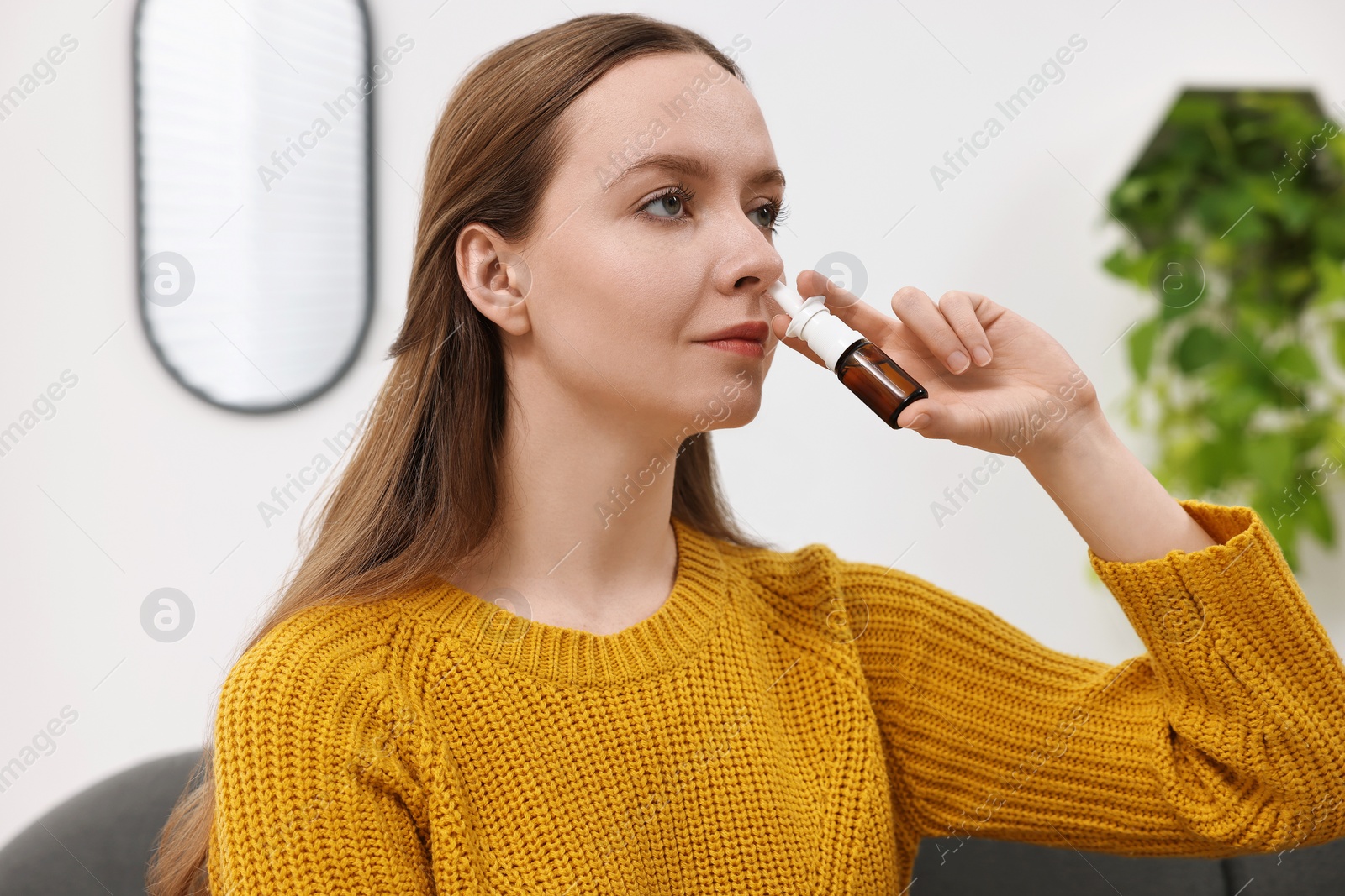 Photo of Medical drops. Young woman using nasal spray indoors