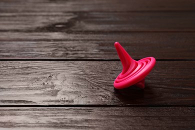 One pink spinning top on wooden table, closeup. Space for text