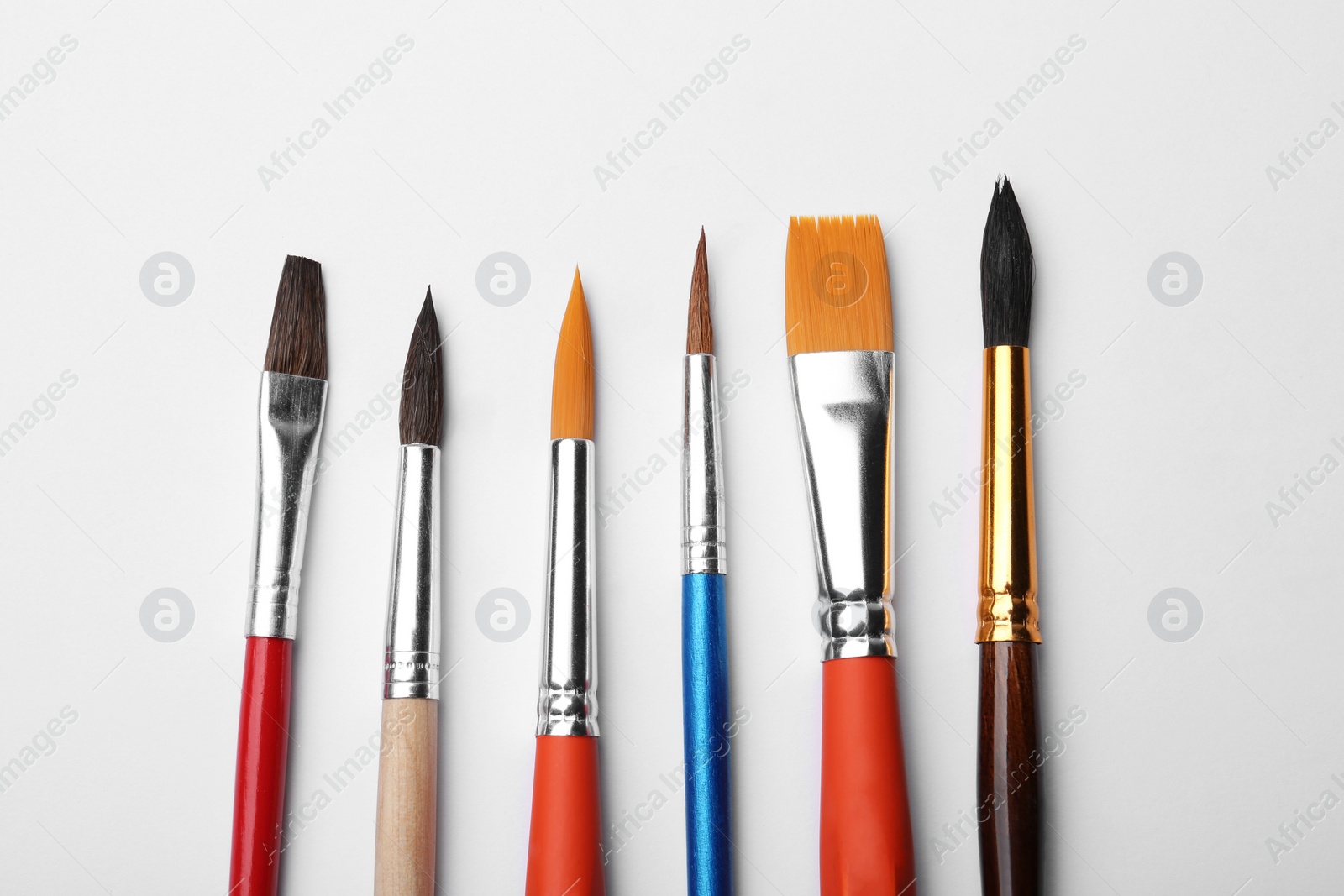 Photo of Different paint brushes on white background, top view