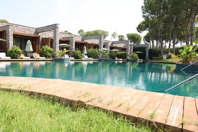 Outdoor swimming pool with wooden deck, sunbeds and umbrellas at resort