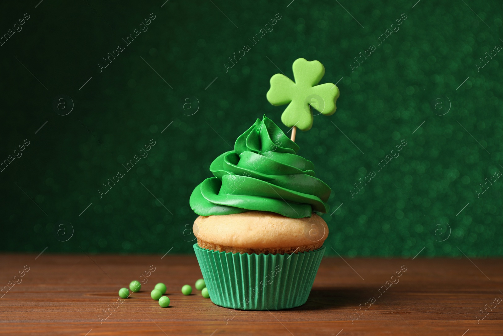 Photo of Delicious decorated cupcake on wooden table. St. Patrick's Day celebration